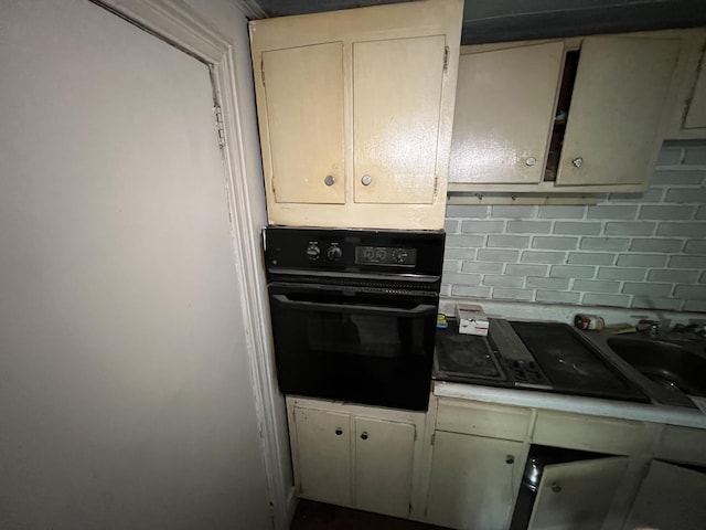 kitchen with decorative backsplash, black appliances, and cream cabinets