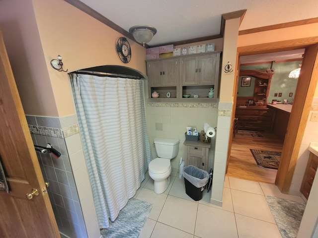 bathroom with tile patterned flooring, tile walls, vanity, ornamental molding, and toilet