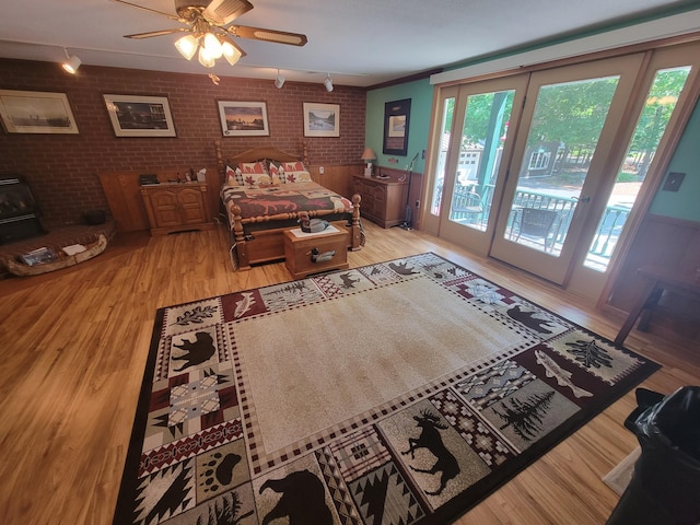 bedroom with brick wall, hardwood / wood-style floors, access to exterior, ceiling fan, and crown molding