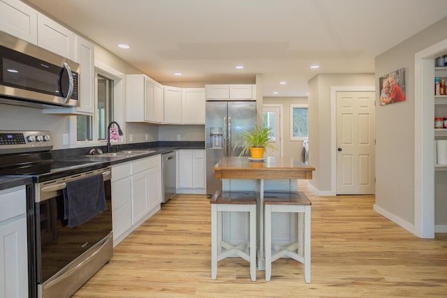 kitchen with white cabinets, appliances with stainless steel finishes, light hardwood / wood-style flooring, and sink