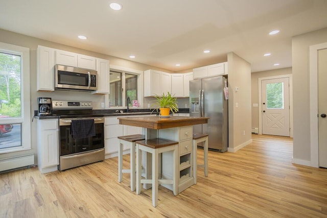 kitchen featuring light hardwood / wood-style floors, a wealth of natural light, white cabinets, and stainless steel appliances