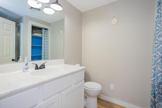 bathroom with toilet, wood-type flooring, and vanity