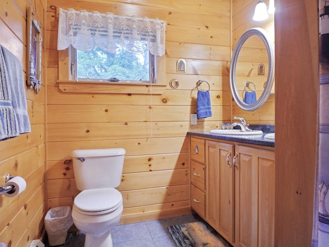 bathroom featuring toilet, vanity, tile patterned floors, and wood walls