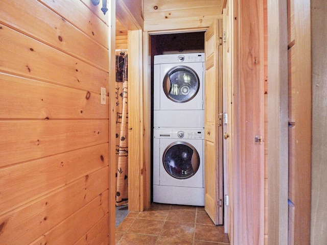 laundry room featuring stacked washer / dryer and wood walls