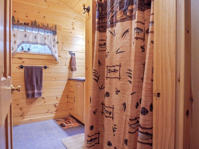 bathroom featuring tile patterned flooring, wooden walls, and vaulted ceiling