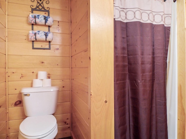 bathroom featuring wood walls and toilet