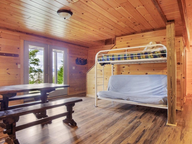 bedroom with wooden walls, wooden ceiling, and hardwood / wood-style flooring