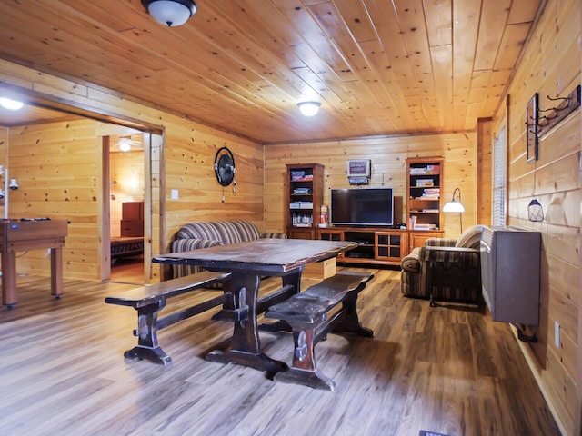 dining space with hardwood / wood-style floors, wooden ceiling, and wooden walls