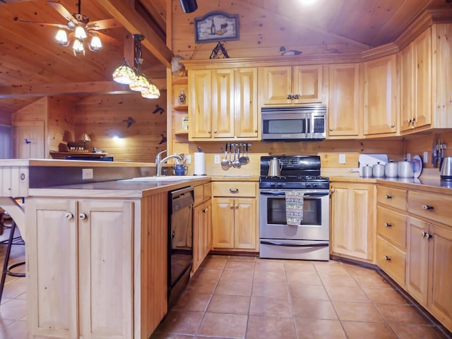 kitchen with sink, wood walls, pendant lighting, lofted ceiling, and appliances with stainless steel finishes