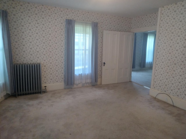 unfurnished bedroom featuring radiator and carpet flooring