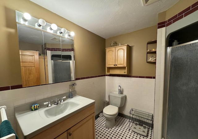 382 Water St, Guilford, ME 04443 - full bath with tile walls, vanity, a shower stall, toilet, and a wainscoted wall