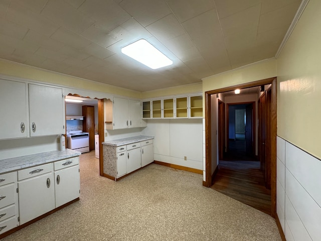 kitchen with white cabinets, light wood-type flooring, ornamental molding, and electric range