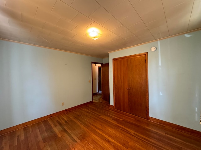 unfurnished bedroom with wood-type flooring, a closet, and ornamental molding