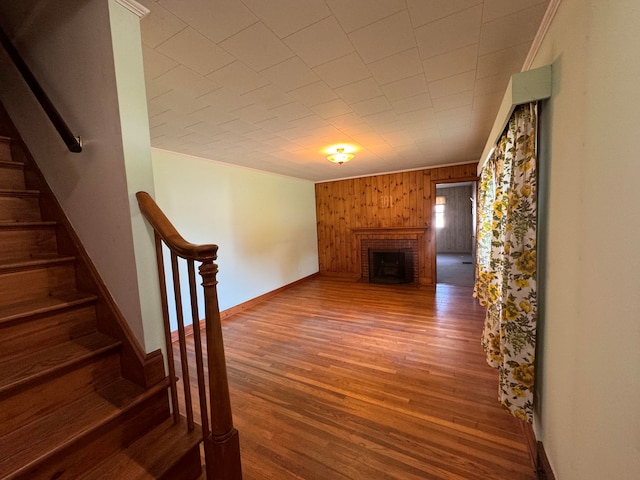 unfurnished living room with a fireplace, wooden walls, and wood-type flooring