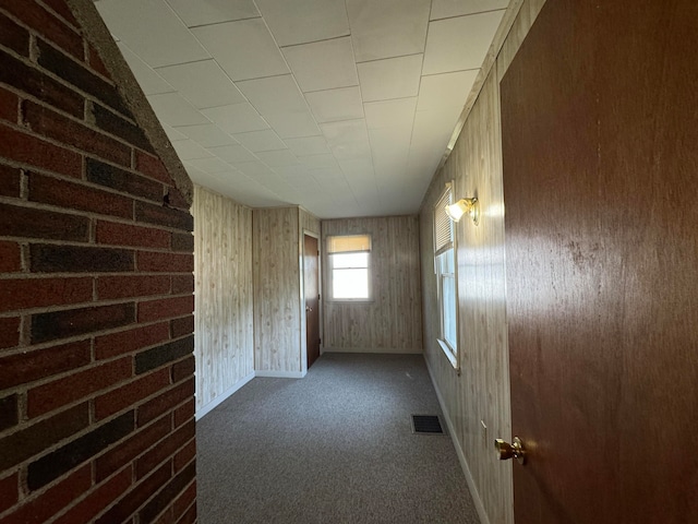 hallway with dark carpet and wooden walls