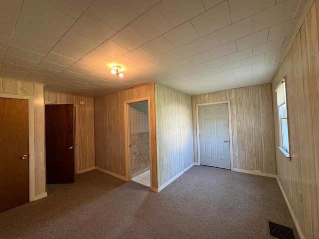 unfurnished bedroom featuring wood walls, carpet flooring, and a closet