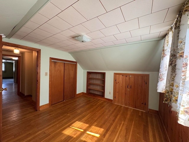 bonus room featuring built in shelves, hardwood / wood-style flooring, and vaulted ceiling