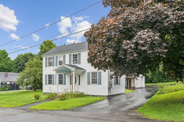 colonial-style house featuring a garage and a front lawn