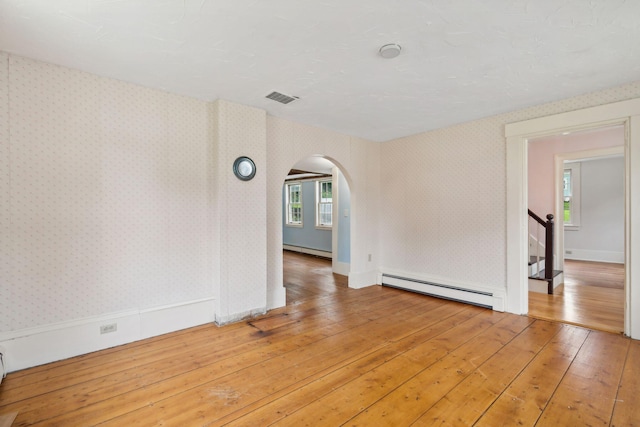 unfurnished room with baseboard heating and wood-type flooring