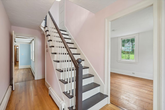 stairway featuring a baseboard radiator and light wood-type flooring