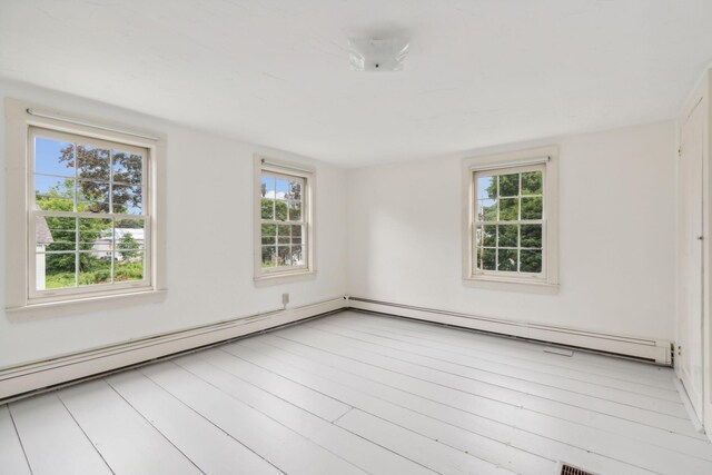 empty room featuring a baseboard heating unit, light hardwood / wood-style flooring, and plenty of natural light