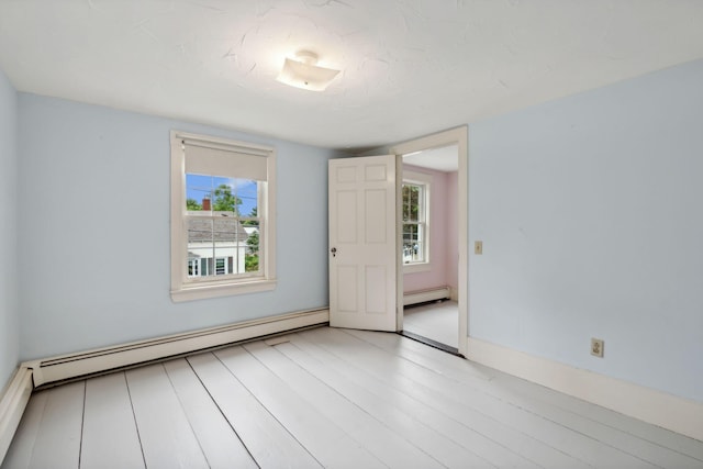 empty room featuring baseboard heating and light hardwood / wood-style floors