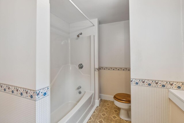 bathroom with toilet,  shower combination, and tile patterned floors