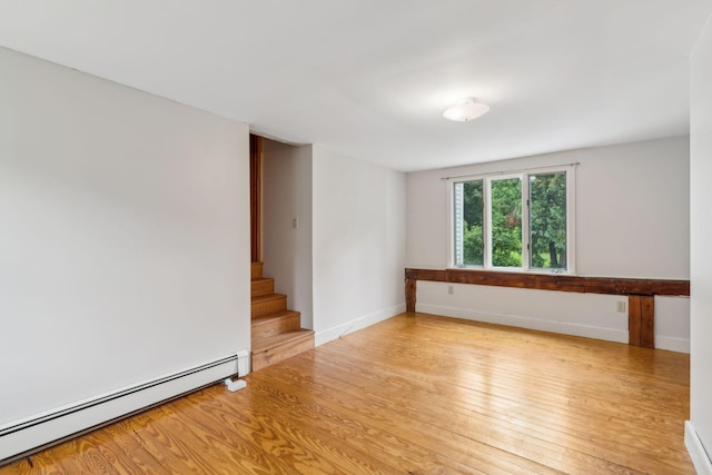 spare room featuring a baseboard heating unit and light hardwood / wood-style flooring