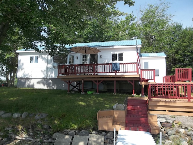 rear view of house with a wooden deck and a lawn