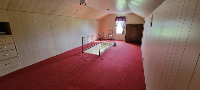 additional living space featuring vaulted ceiling, wood walls, and carpet flooring