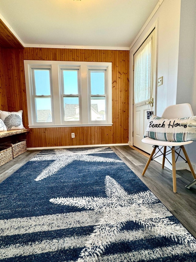 living area with crown molding, wood-type flooring, and wooden walls