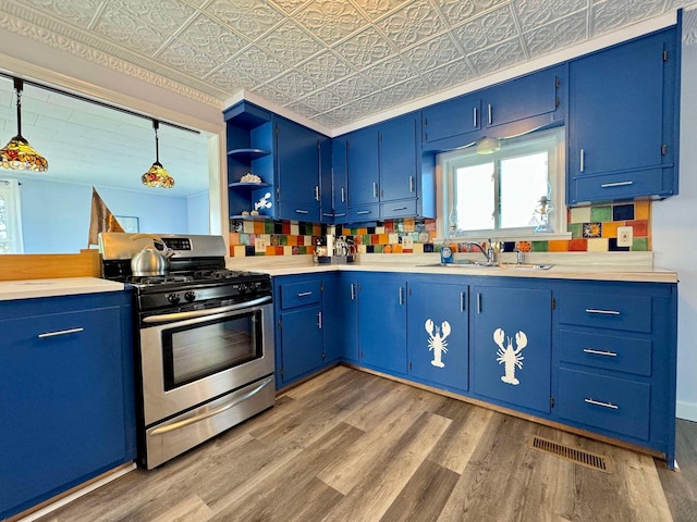 kitchen featuring blue cabinets, sink, gas range, wood-type flooring, and hanging light fixtures