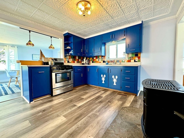 kitchen featuring hanging light fixtures, stainless steel gas range oven, and blue cabinets