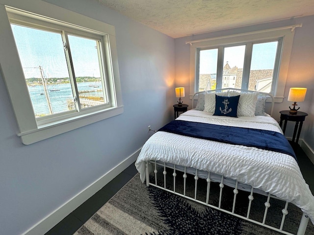 bedroom featuring a water view and a textured ceiling