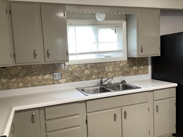 kitchen featuring fridge, tasteful backsplash, and sink