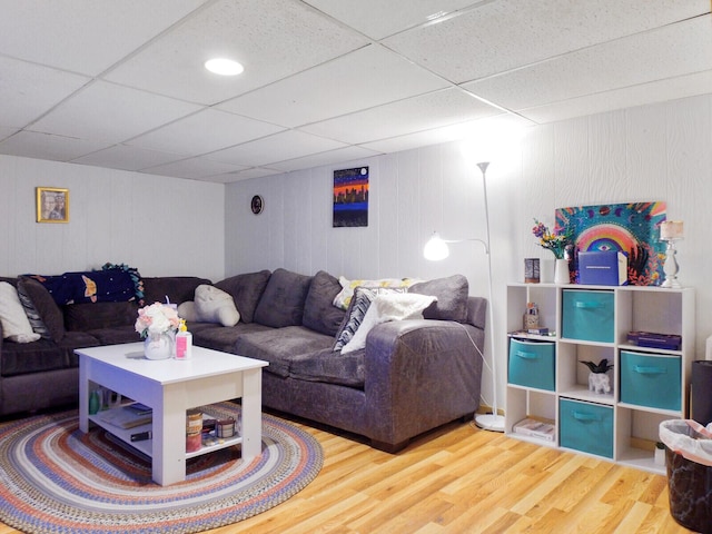 living room featuring wooden walls, a drop ceiling, and hardwood / wood-style flooring