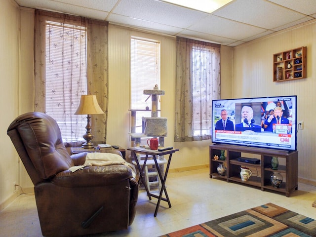 living room with a drop ceiling and wood walls