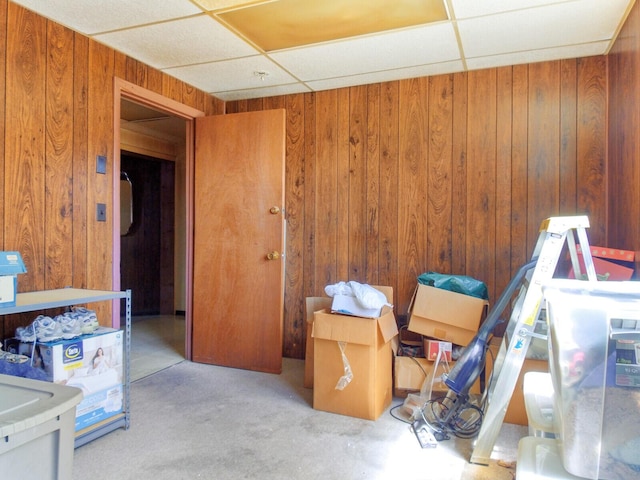 interior space with a paneled ceiling and wood walls