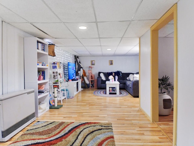 living room with hardwood / wood-style floors, heating unit, and a drop ceiling