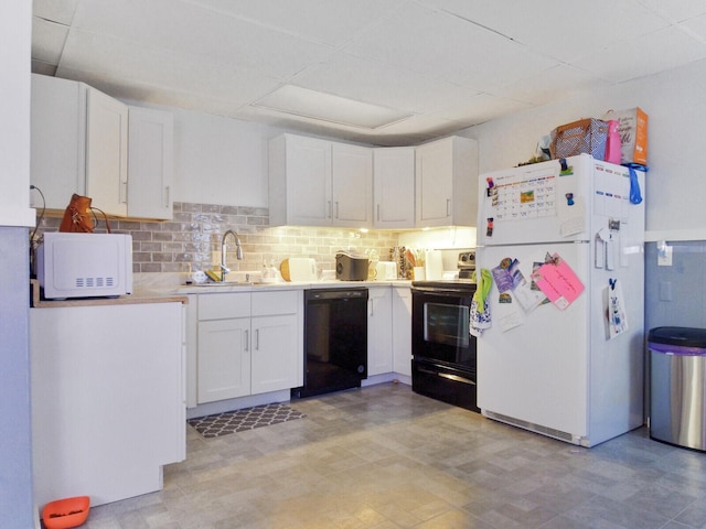 kitchen featuring a drop ceiling, black appliances, sink, decorative backsplash, and white cabinetry