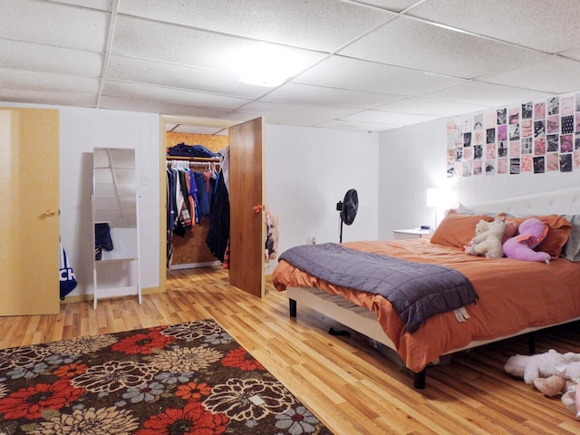 bedroom featuring hardwood / wood-style flooring, a paneled ceiling, and a closet