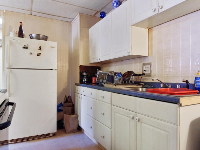 kitchen with a drop ceiling, sink, tasteful backsplash, white fridge, and white cabinetry