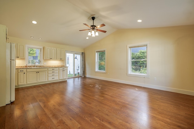 unfurnished living room with ceiling fan, sink, hardwood / wood-style flooring, and lofted ceiling