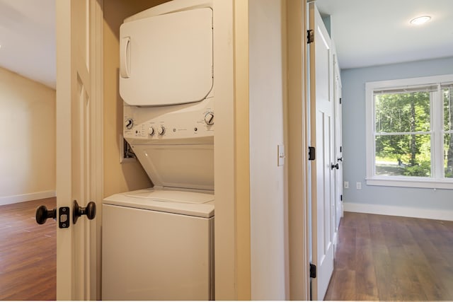 laundry area with stacked washing maching and dryer and dark hardwood / wood-style floors