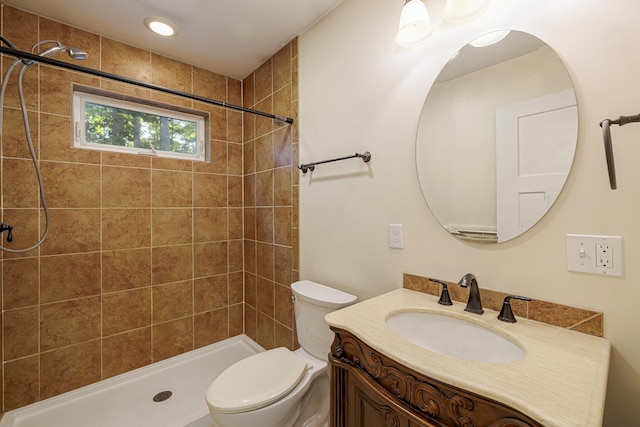 bathroom with vanity, toilet, and tiled shower