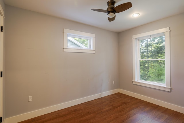 empty room with dark wood-type flooring, ceiling fan, and a wealth of natural light