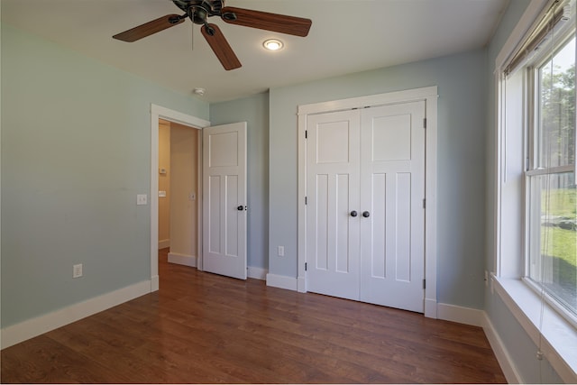 unfurnished bedroom featuring ceiling fan, a closet, and dark wood-type flooring