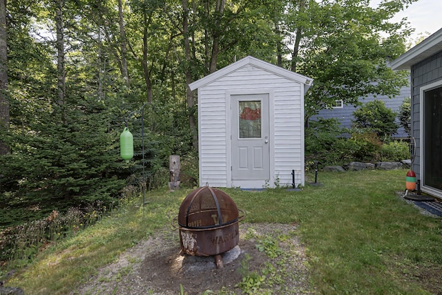 view of outbuilding featuring an outdoor fire pit and a yard