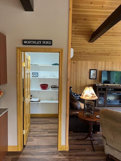 interior space featuring wood walls, beam ceiling, and wood finished floors