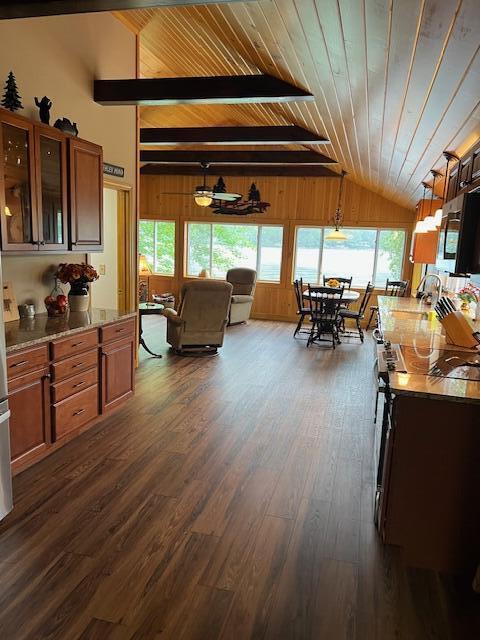interior space featuring wood ceiling, lofted ceiling with beams, dark wood-style floors, and wood walls